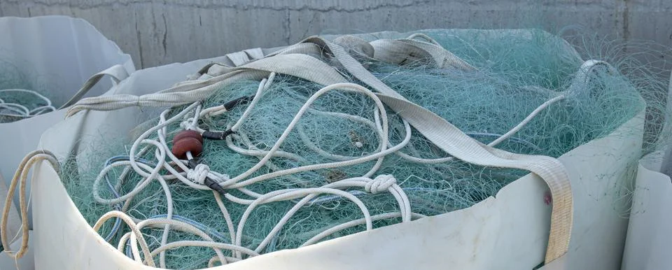 Large white bulk container filled with green nylon fishing nets and ropes o.. Stock Photos