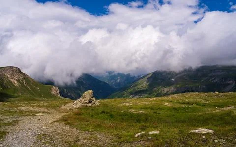 Large white clouds float across blue sky above mountain peaks along Grossgl.. Stock Photos