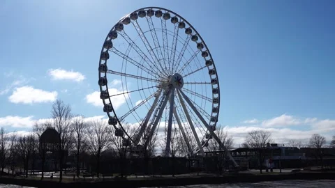 Large white ferris wheel stands against a bright blue sky with light clouds Stockbeeldmateriaal 334330640