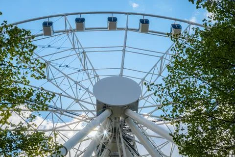 Large white ferris wheel structure against a blue sky with clouds, surround.. Stock Photos