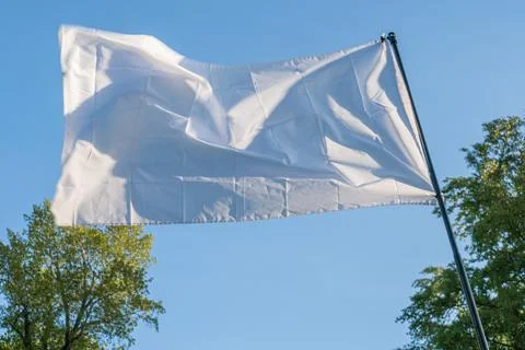 Large white flag with rounded corners, billowing in wind against a blurred .. Stock Photos