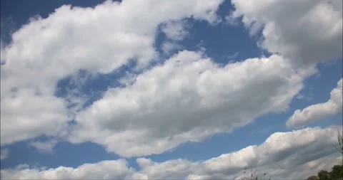 Large white fluffy clouds floating in the blue sky in a time-lapse video Stock Footage 275351091