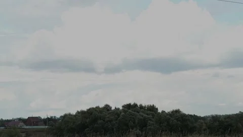 Large white fluffy clouds hanging over green trees and houses. Stock Footage 342949026
