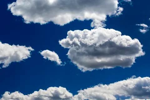 Large white fluffy clouds highlighted with deep blue sky Stock Photos