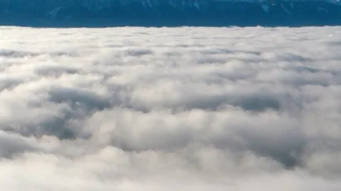 Large white fluffy clouds or fog approaching the mountains and blue sky Stock Footage 256237954