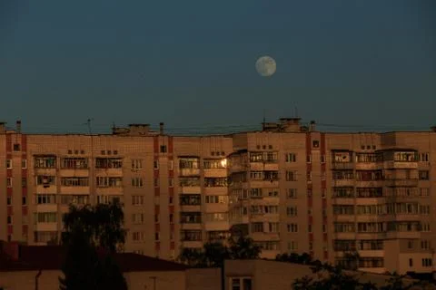 Large white full moon on clear blue over an urban high building Stock Photos