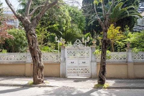 Large white gate surrounded by trees and plants in a garden setting in a re.. Stock Photos