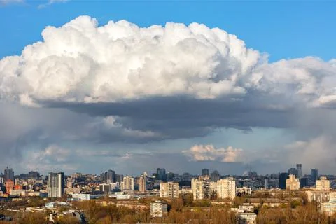A large white-gray cloud hung over the city and was illuminated by the spring Stock Photos
