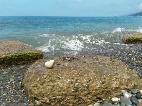 A large white heart-shaped stone on the coastal breakwater. The increasing wa Stock Photos