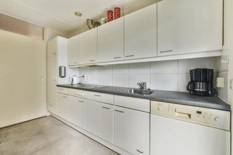 A large white kitchen with white cabinets and a sink Stock Photos