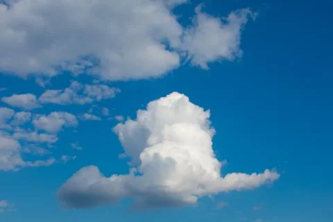 Large white orange cloud against the blue sky at sunset. Stock Photos