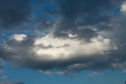 Large white orange cloud against the blue sky at sunset. Stock Photos