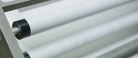 Large white paper going over multiple rollers on a metal feeding machine CU Stock Footage 112893462