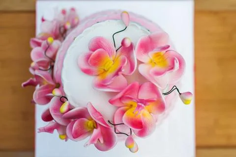 Large white-pink holiday cake decorated with flowers on a wooden table close- Stock Photos