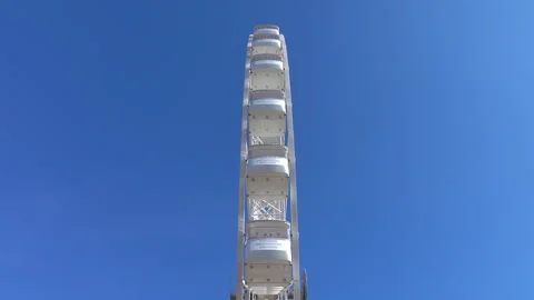 Large white spinning ferris wheel against at clean blue sky background 4K. 스톡 동영상 257109337