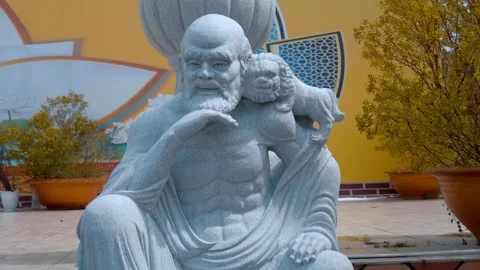 A large white stone sculpture of a sage or monk, with a figure of a lion Stock-Footage 333365243