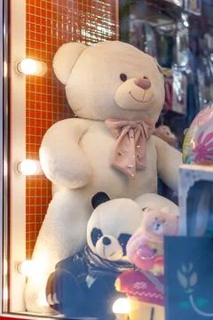 A large white teddy bear and other toys in the shop window. Stock Photos