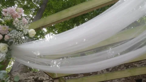 A large white veil adorned with pale pink and white flowers for a forest wedding Vídeo Stock 336659906
