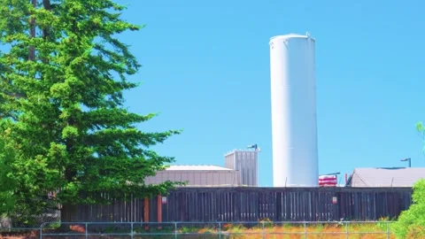 Large white vertical industrial storage silo tank behind wooden fence 库存影片 335907154