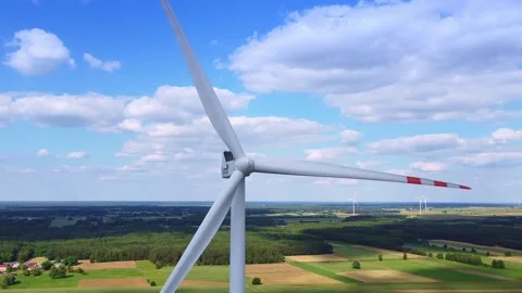 Large white wind turbine spinning in rural farmland landscape Video stock 342590941