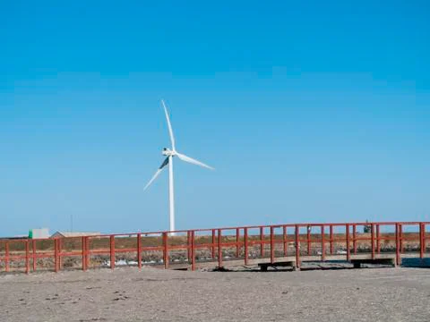 Large white windmill on a beach with bright blue sky - representing green and su Stock-Fotos