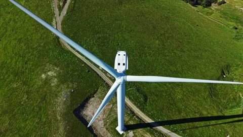 Large wind turbine stands on green field in rural area near dirt path during Stock Footage 337946656