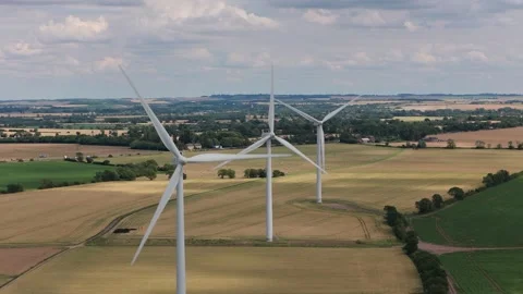 Large Wind Turbines Spinning in Green Farm Fields Under a Cloudy Blue Summer Sky Stock Footage 341838060