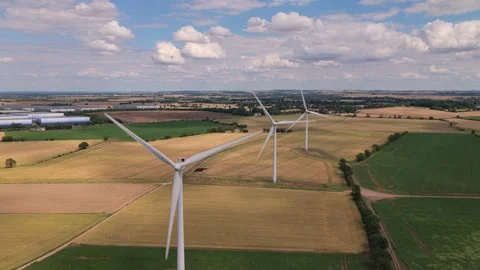 Large Wind Turbines Spinning Over Rural Fields in England During a Sunny Summer Stock Footage 341838193
