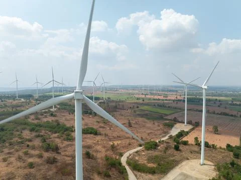 Large Wind Turbines Standing In Rural Agricultural Landscape Under Blue Sky.. Stock Photos