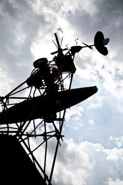 A large windmill is silhouetted against a mostly cloudy sky with sunlight Foto stock