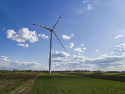 Large windmills stand in green fields against a blue sky Stock-Fotos
