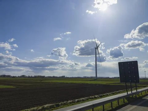 Large windmills stand in green fields against a blue sky Stock Photos