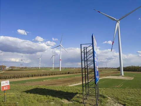 Large windmills stand in green fields against a blue sky Stock Photos