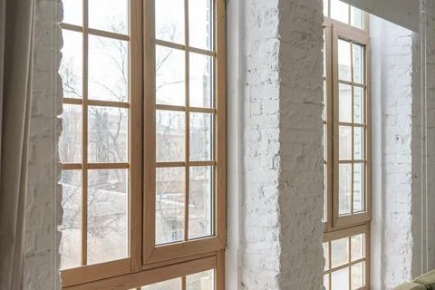 Large windows with wooden frames in loft interior with white brick walls in.. Foto stock