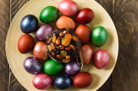 A large wooden plate with an Easter cake and flowered eggs on a rustic wood.. Stock Photos
