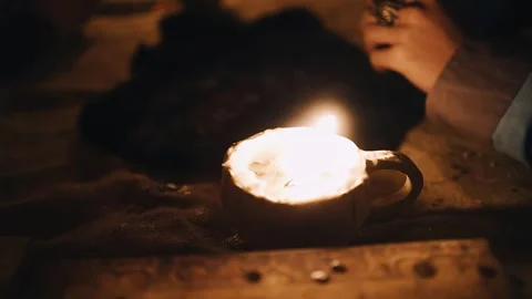 On a large wooden table there is a cup with a candle that illuminates the room Stock Footage 257058762
