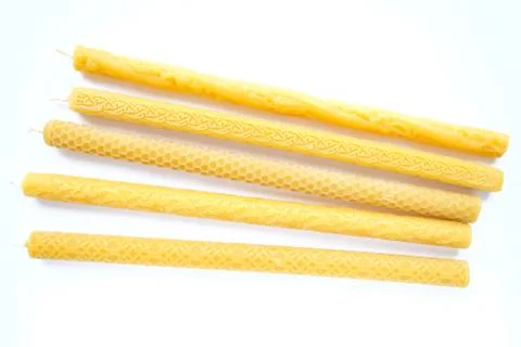 Large yellow candles with different cut patterns on white. Lie side by side 스톡 사진
