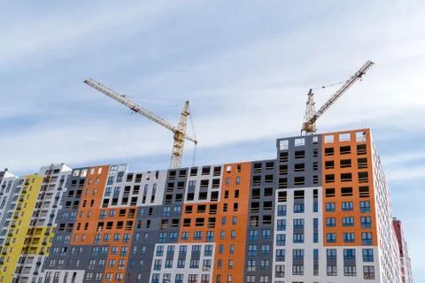 Large yellow construction crane, multi-storey house against the blue sky Stock Photos