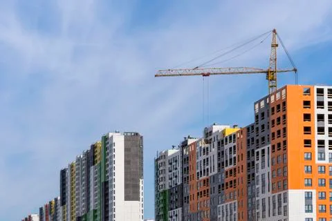 Large yellow construction crane, multi-storey house against the blue sky Stock Photos