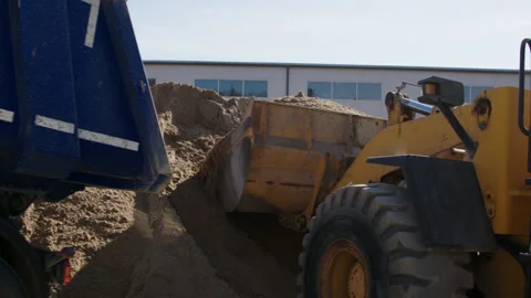 Large yellow construction machine at a cement plant, loading the front trailer Stock Footage 236681124