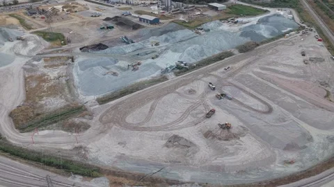 Large yellow construction vehicles move across a vast gravel quarry, shifting Stock Footage 346422622