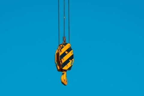 Large yellow crane hook on a background of blue sky Stock Photos