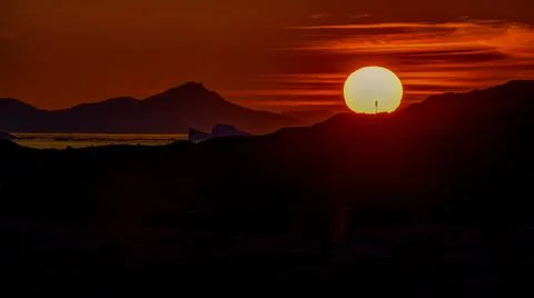 A large yellow disk of the setting sun above the horizon Stock Photos