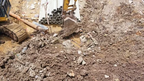 A large yellow excavator uses its bucket to level the ground in a construct.. Stock Footage 300078929