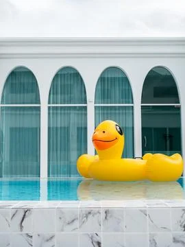 Large yellow inflatable duck floating in outdoor swimming pool at modern re.. Stock Photos