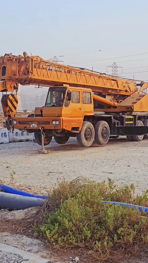 Large yellow mobile crane truck parked on a dusty outdoor construction site Video stock 344771553