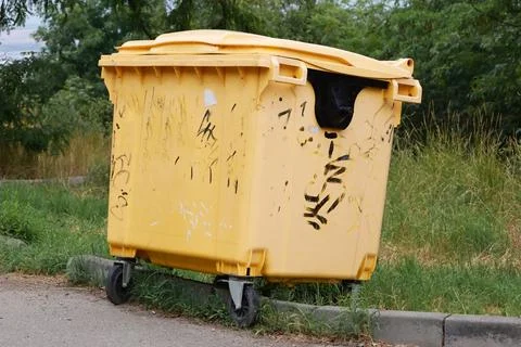Large yellow plastic dumpster on wheels outdoors Stock Photos