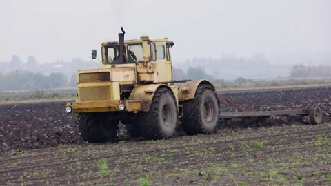 Large yellow Russian tractor with a plow plows up the soil in a cabbage field Stock Footage 169075952