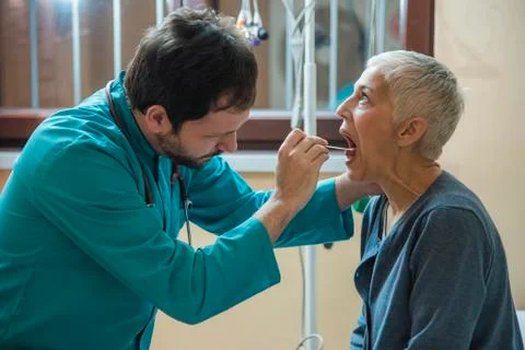 Laryngitis or tonsil problem a senior woman is checking with her doctor Stock Photos