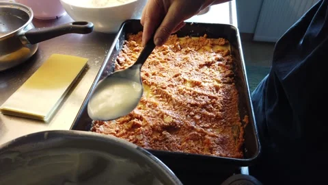 Lasagna Preparation With Spoon Layering Sauce Over Pasta In A Baking Tray Stock Footage 332561902
